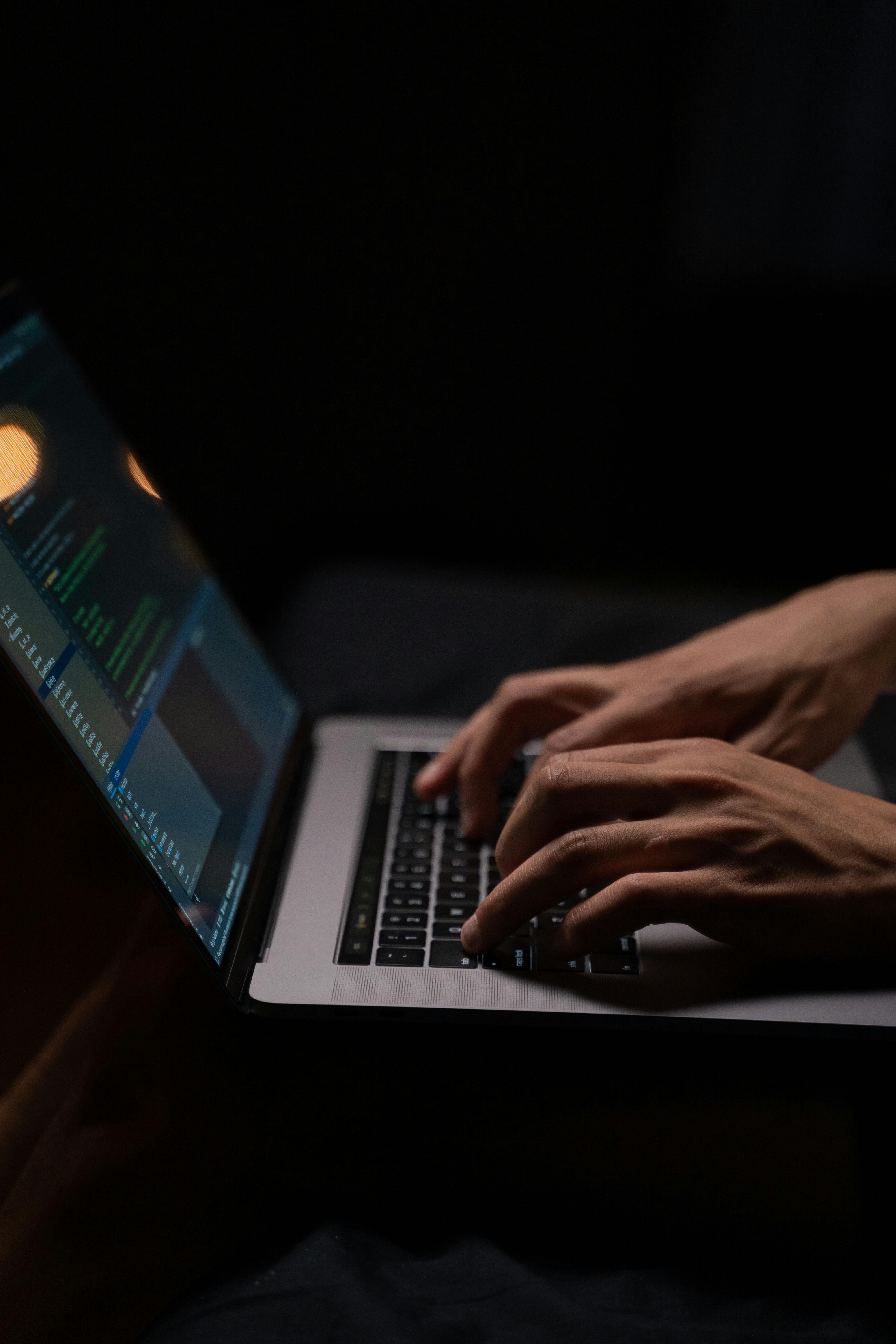 Manos tecleando código en un portátil en un entorno oscuro, representando el trabajo técnico en terminal y CI/CD