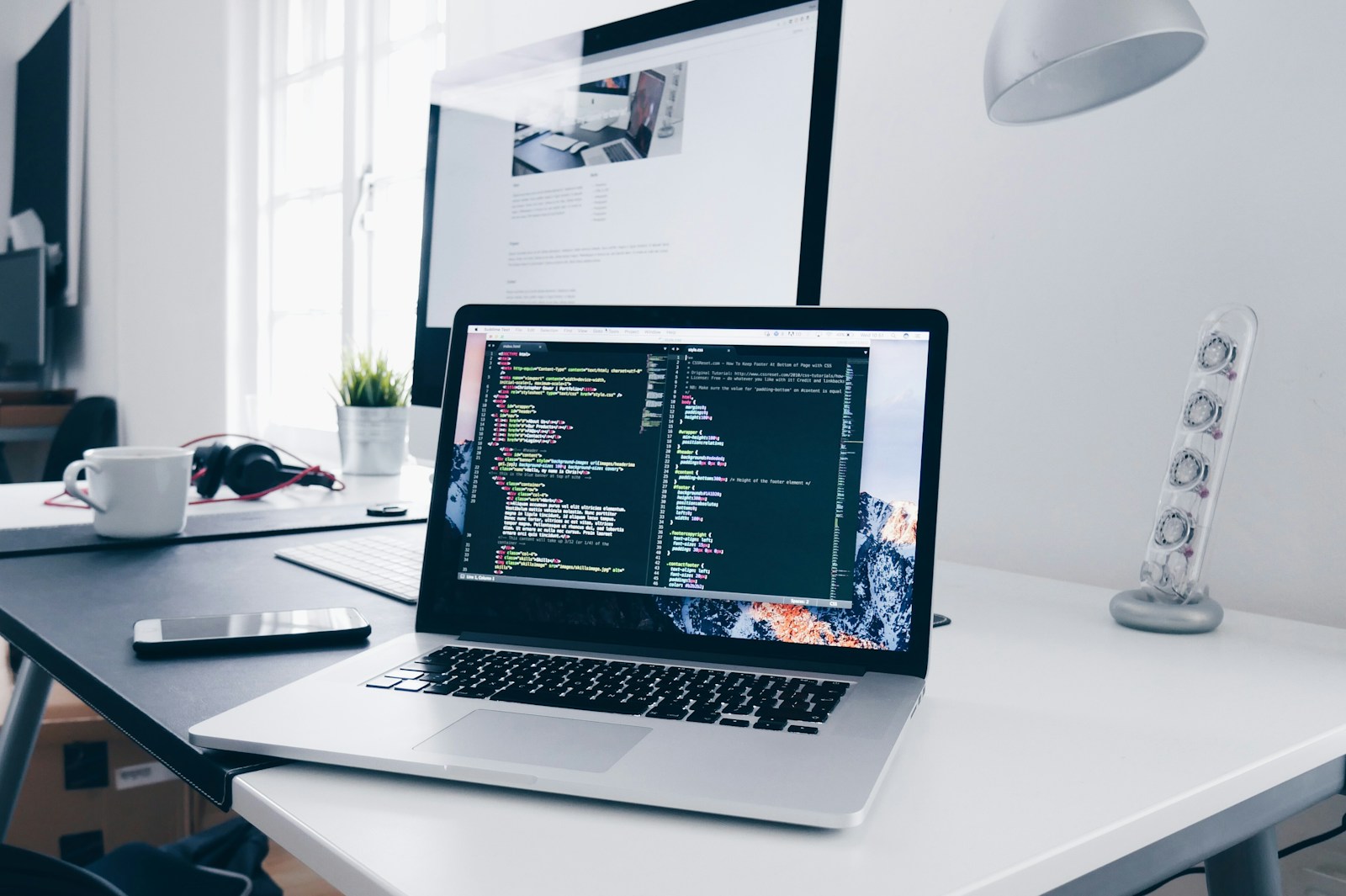 Laptop con código en pantalla en escritorio minimalista de desarrollo web